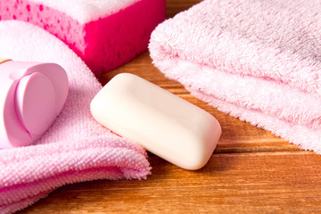 Obraz na płótnie Canvas Pink sponges for shower ,a towel, soap, shampoo, body cream on wooden background .Cleansing spa accessories