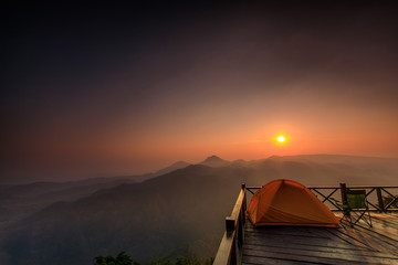 The orange hiker's  tent on the wooden terrace in  high mountain.