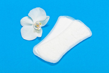 White Sanitary pads and flower white Orchid on a blue background.