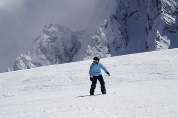 Snowboarder downhill on snowy ski slope in high mountain
