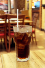 Fresh cola with ice cubes, restaurant background selective focus on glass.