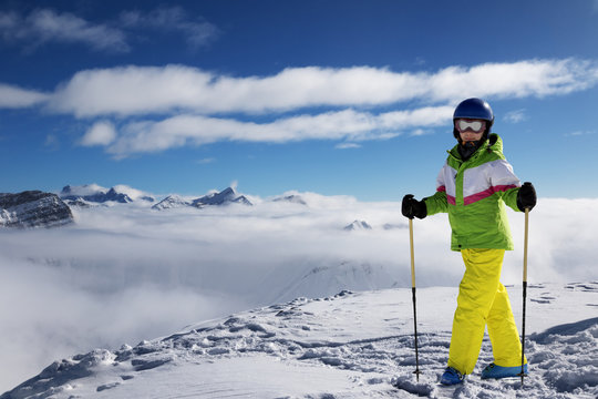 Young skier at top of snowy mountains at sun winter day