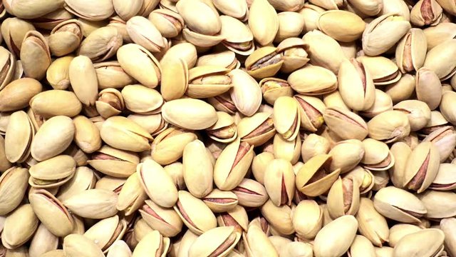 4K view of pile of pistachio nuts in the shell as background.       