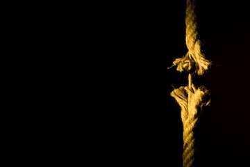 Frayed rope breaking on a dark background