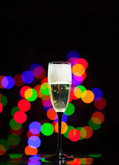 glass full of champagne over holiday lights. Holiday. Party/ Cheers