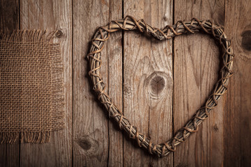 Rustic background with heart shaped branches and jute on a old wooden table.