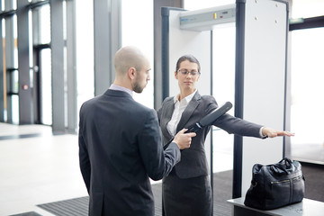 Young female passenger stretching her arm while security of airport scanning it by gates