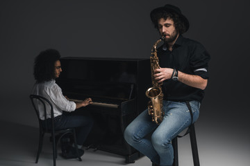 Fototapeta premium man playing saxophone while his partner playing piano blurred on background