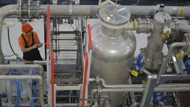 Engineer looking at the high pressure air compressor and controls the readings on the smartphone.