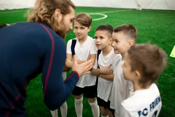 Kussenhoes Young football trainer talking to team of little players on the field during break between games © pressmaster