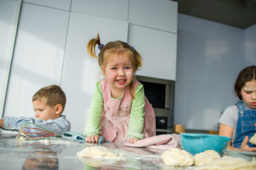 Three children prepare something from the dough.