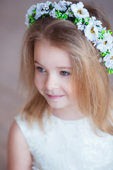 Naklejka premium Portrait of a cute little girl in wreath of flowers