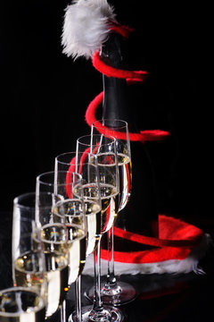 Celebrating new year, birthday, xmas party. Bottle of champagne in a bucket on black backgroud. Santa's hat