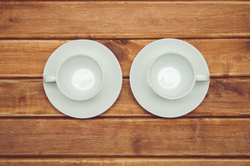 Two empty white Cup with saucer on a wooden background, top view . Crockery for coffee and tea