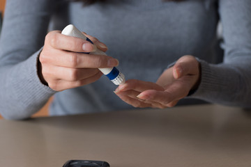 Close-up of woman hands using lancet on finger to check blood sugar level by Glucose meter. Health care concept.