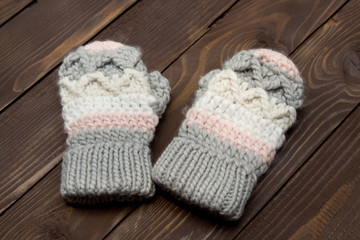 Fototapeta na wymiar Warm knitted gloves on wooden background. Clothes for winter.