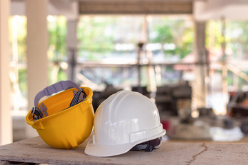 Yellow and white helmets are placed on the wooden table inside the construction area.