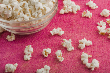 popcorn in a glass plate, on a pink background