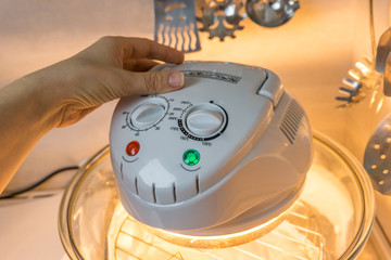 A close-up of hand  of woman using halogen oven, an innovation in the process of cooking food for a healthy diet. Shallow depth of focus.