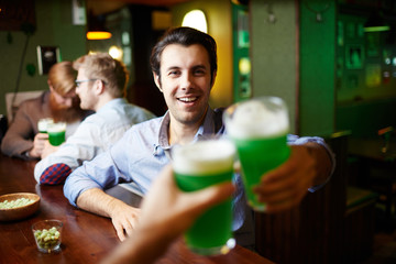 Ecstatic man toasting with one of his friends while spending evening in pub