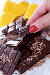 tablet and pieces of dark chocolate with woman finger