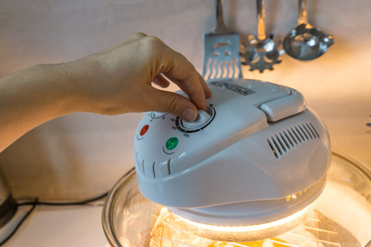 A close-up of hand  of woman using halogen oven, an innovation in the process of cooking food for a healthy diet. Shallow depth of focus.