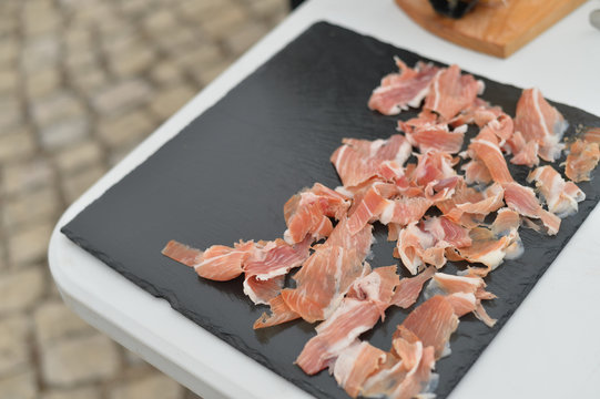 Prosciutto or jamon serrano. Close up on cutting traditional Italian Spanish ham. Slicing prepared hamon gastronomy background
