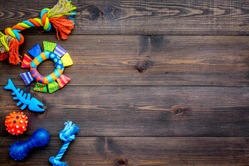 Toys for pets dog and cat. Rubber and textile accessories on dark wooden background top view copy space