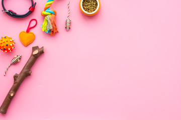 Pet accessories. Toys near bowls with animal feed, collar on pink background top view copy space