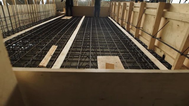 laborers are standing and walking over reinforcing cage floor slab in a construction site in working day