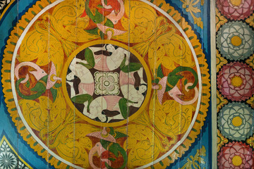 Asian women and myth animals on ceiling of ancient Buddhist temple with paintings