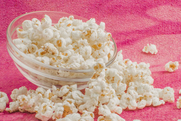 popcorn in a glass plate, on a pink background
