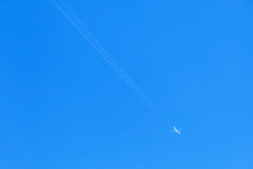 Jet plane with long trail in blue sky