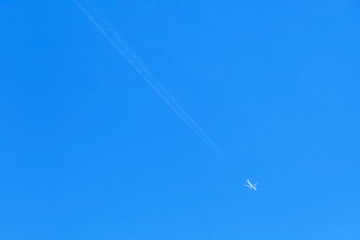 Jet plane with long trail in blue sky