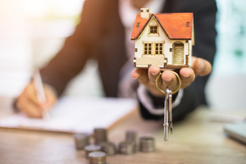 Businessman signs contract behind home architectural model