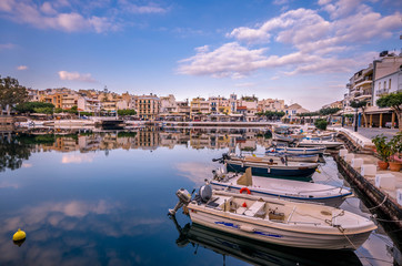 Agios Nikolaos Crete -Amazing view with reflections at Voulismeni lake. Dramatic sky with colorful buildings of one of the most popular touristic destination of Crete.