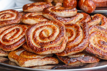 Fresh, hot sausages cooked on the grill, outdoors, on the coals.