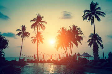 Obraz na płótnie Canvas Silhouettes of palm trees on a tropical sea beach during sunset.