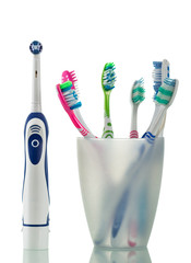 Modern electric and manual toothbrushes stand in glass isolated on white