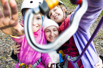 Mother and young daughters looking together through carbine after climbing in adventure park on...