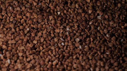 Buckwheat falls on a white plate, a black background.