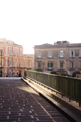 Une rue pavée dans le soleil avec un palais ancien de Syracuse en Sicile.