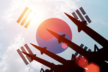 Antiaircraft rockets silhouettes on background of South Korea flag. Sunny.