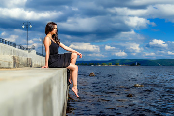 young beautiful girl sitting on the river bank