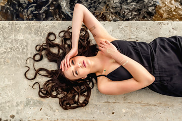 young beautiful girl lies on stones with flowing hair