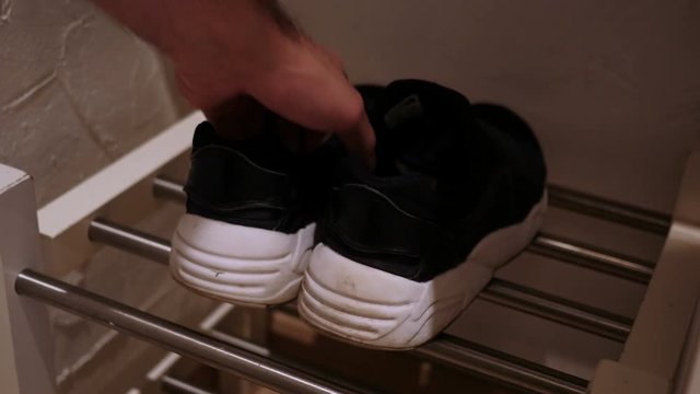 Close Up of Hands Putting Shoes on Shoe Reck
