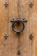 Ancient wooden entrance door with handle and fleur-de-lis ironwork. Saint-Denis, France