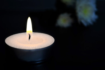 Fototapeta na wymiar White burning candle on dark background