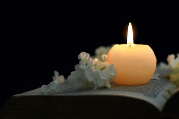 Candle and flowers on opened book