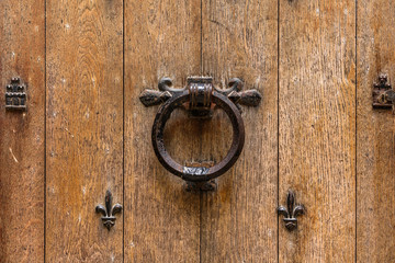 Ancient wooden entrance door with handle and fleur-de-lis ironwork. Saint-Denis, France